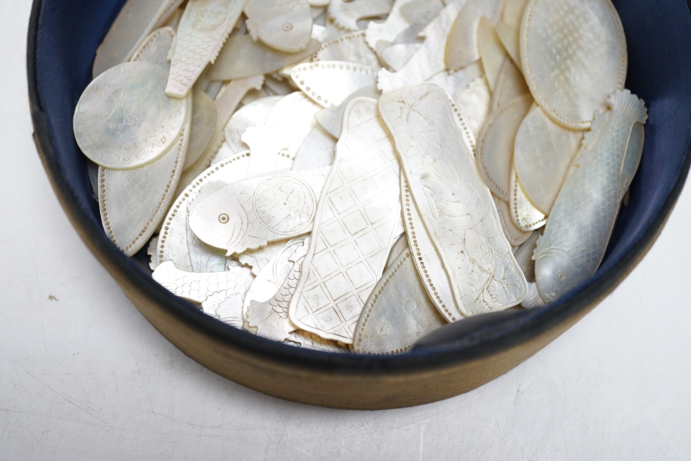 A collection of Chinese mother of pearl fish and other shaped counters